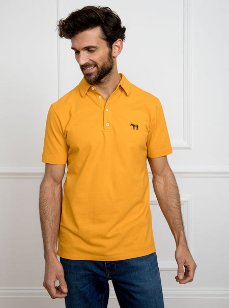 Man wearing gold yellow polo shirt in 100% cotton with Newmarket 875 horse logo embroidered on the front.
